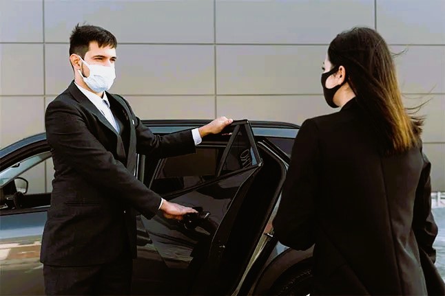 Driver assisting a passenger into a taxi